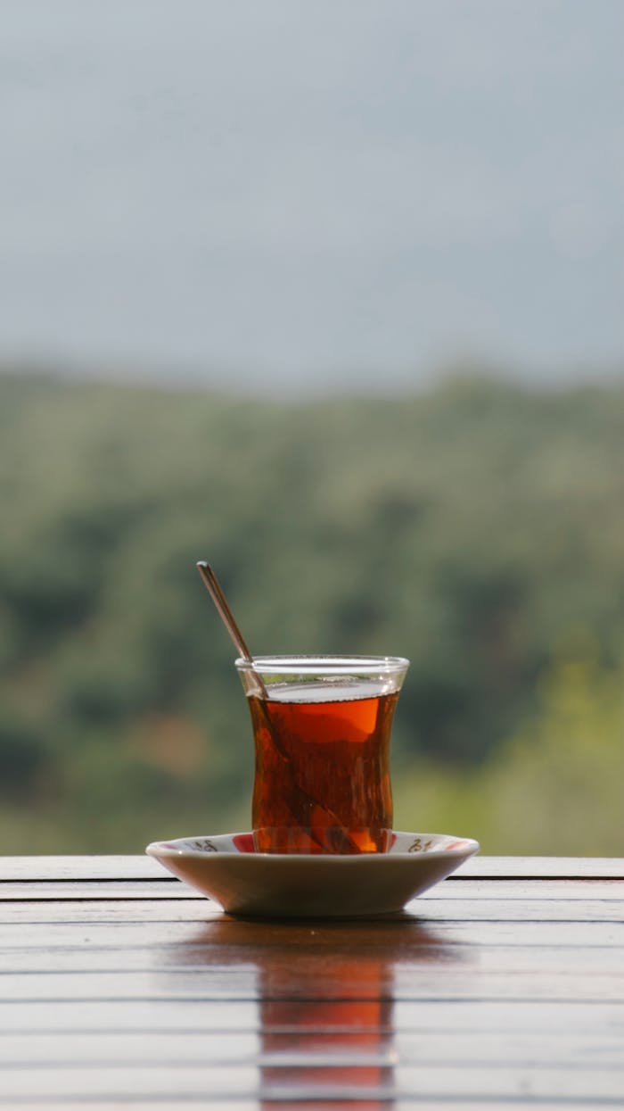 Traditional Turkish tea served in a tulip glass with an outdoor view, creating a relaxing ambiance.